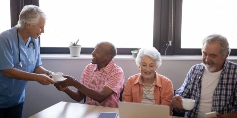 Female Nurse Serving Coffee to Elderly Residents During Morning Gathering at an Assisted Living Facility