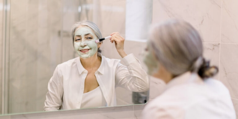 Senior Woman Applying a Face Mask in a Bathroom at an Assisted Living Facility