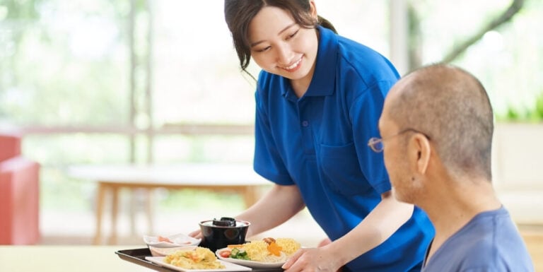 Nursing Staff Serving Meal to Resident at Assisted Living Facility